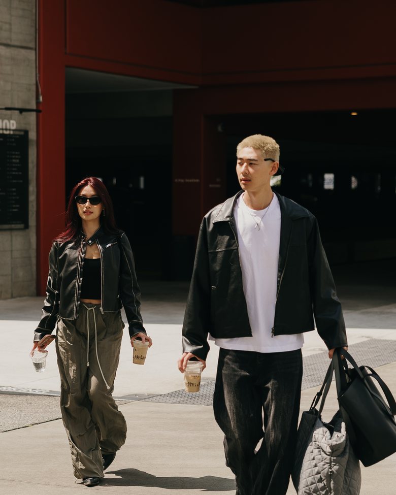 Scott Ho and Seolah walking out of a building on a weekday afternoon, iced coffees in hand