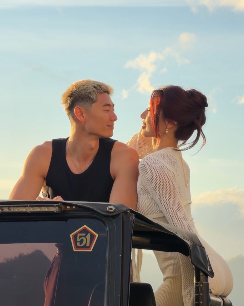 Scott Ho and Seolah leaning on the roll bar of a jeep at sunset, looking at each other
